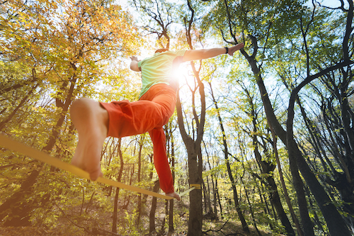 wide,angle,male,tightrope,walker,balancing,barefoot,on,slackline,in